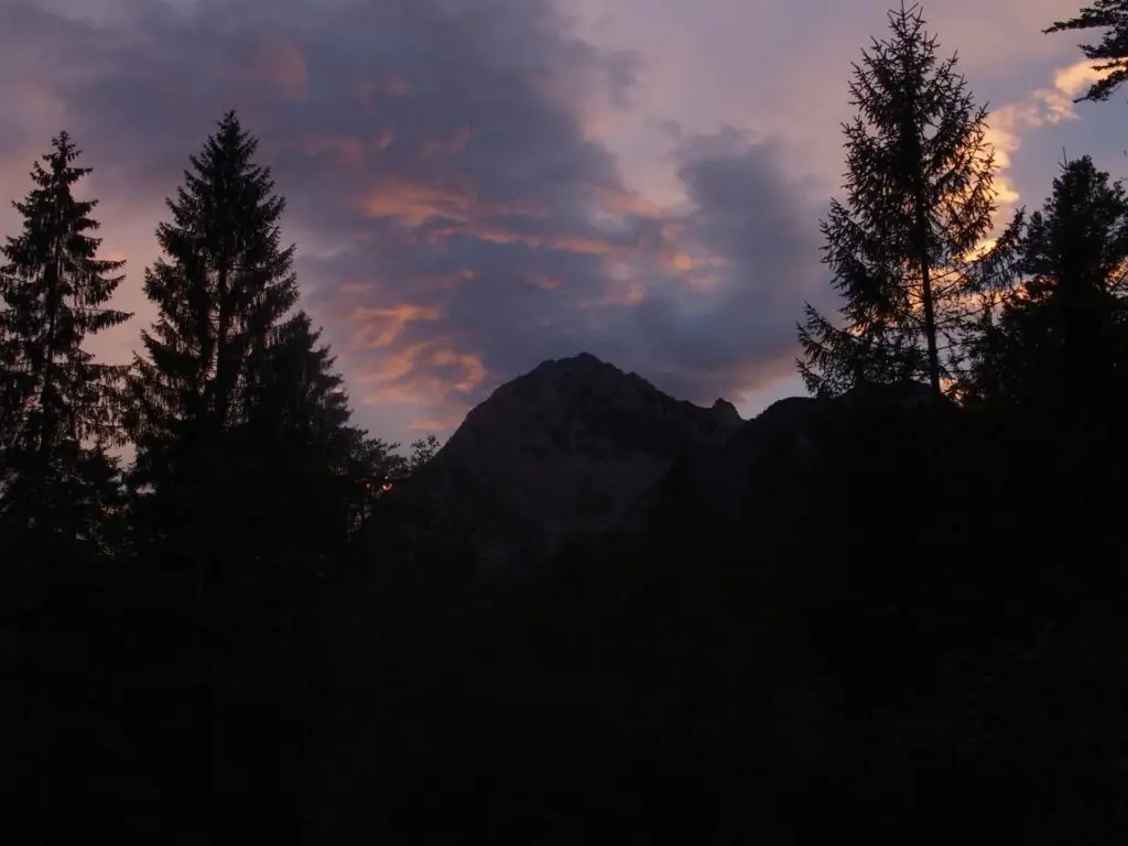 Tente et vélo de voyage posés dans un champ au coucher du soleil